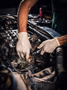 car mechanic at work in repair garage checking motor